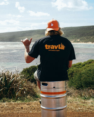 Travis Fimmel in travla logo shirt-black sitting on keg